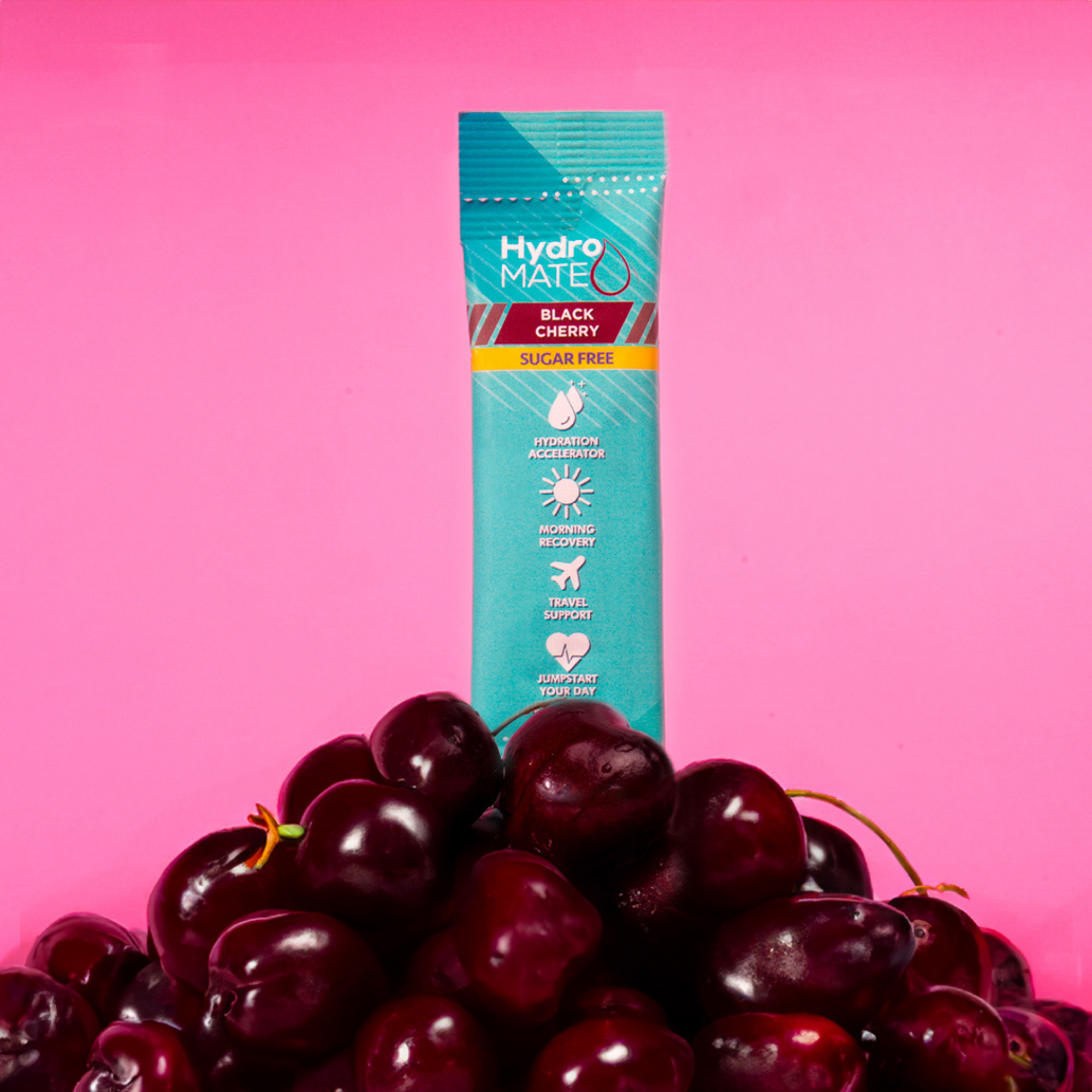 Sugar-free Hydro Mate Black Cherry drink mix packet stands against a bright pink background, showcasing the product's refreshing flavor alongside a pile of ripe black cherries. 
 
 ```alt="Sugar-free Hydro Mate Black Cherry drink mix with fresh black cherries"```